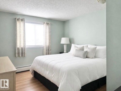 Room featuring wood-finish flooring, a window with blinds, and light-toned walls - #106 10620 104 St Nw, Edmonton, AB - Indoor Photo Showing Bedroom
