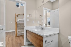 Wall-mounted vanity with wood-finish cabinet and white countertop, undermount sink with chrome-finish faucet, and large frameless mirror - 