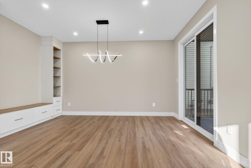 Built-in cabinetry with wood-finish shelving, contemporary pendant lighting, recessed ceiling lights, wood-finish flooring, and sliding glass doors - 9736 73 Avenue Nw, Edmonton, AB 