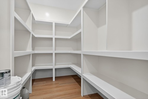 Expansive walk-in pantry with extensive built-in shelving, white finish, and wood-finish flooring - 9736 73 Avenue Nw, Edmonton, AB 