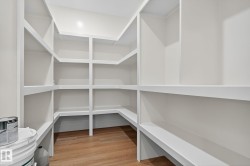 Expansive walk-in pantry with extensive built-in shelving, white finish, and wood-finish flooring - 