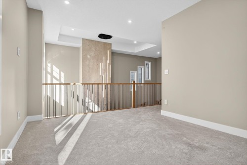 Carpeted loft area featuring a tray ceiling, recessed lighting, and a modern metal and wood railing - 9736 73 Avenue Nw, Edmonton, AB 