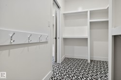 Built-in coat rack with five hooks, custom shelving, multiple hanging rods, and patterned floor tiling - 