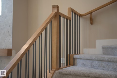 Carpeted staircase featuring wood railing with metal balusters - 9736 73 Avenue Nw, Edmonton, AB 