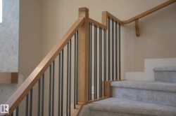 Carpeted staircase featuring wood railing with metal balusters - 