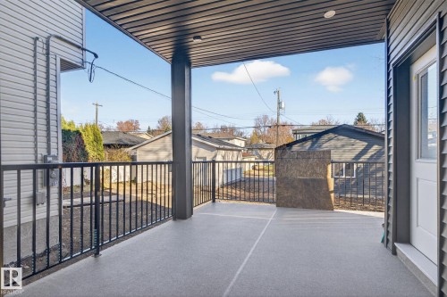 Covered patio with a light gray textured finish and black metal railings - 9736 73 Avenue Nw, Edmonton, AB 