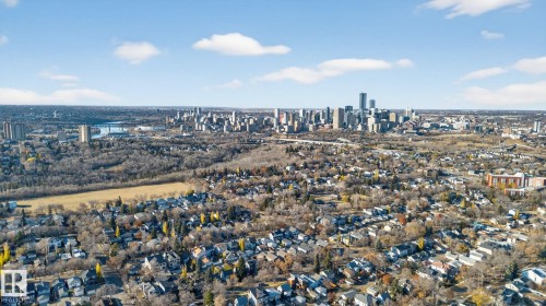 Urban skyline visible in the distance, featuring multiple high-rise structures, surrounded by established residential areas with varied rooflines and a significant expanse of natural tree cover - 9736 73 Avenue Nw, Edmonton, AB 