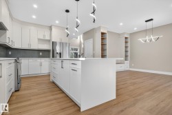 Kitchen featuring white cabinetry, a large center island, stainless steel appliances, and wood-finish flooring - 