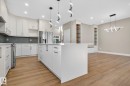 Kitchen featuring white cabinetry, a large center island, stainless steel appliances, and wood-finish flooring - 9736 73 Avenue Nw, Edmonton, AB 