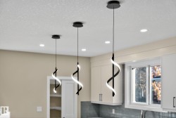 Recessed ceiling lights, white shaker-style cabinetry, a white window frame, and a subway tile backsplash - 
