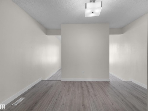 Wood-finish flooring with white trim, complemented by a semi-flush mount ceiling fixture - #47 1904 48 St Nw, Edmonton, AB - Indoor Photo Showing Other Room