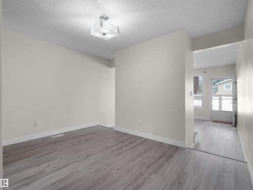 Neutral wall paint, wood-finish flooring, and a contemporary ceiling light fixture - #47 1904 48 St Nw, Edmonton, AB - Indoor Photo Showing Other Room