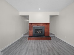 Wood-finish flooring with a gas fireplace featuring a wood surround and black hearth - 
