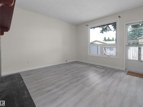 Expansive room featuring wood-finish flooring, a large window, and light-toned walls - #47 1904 48 St Nw, Edmonton, AB - Indoor Photo Showing Other Room