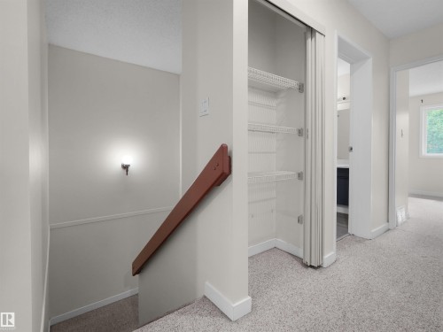 Carpeted hallway featuring a built-in closet with wire shelving - #47 1904 48 St Nw, Edmonton, AB - Indoor Photo Showing Other Room