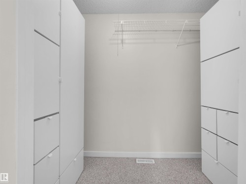Built-in storage cabinetry with integrated drawers, wire shelving, and neutral carpeting - #47 1904 48 St Nw, Edmonton, AB - Indoor