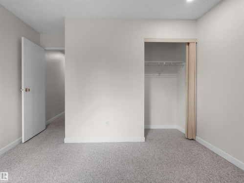 Wall-to-wall carpeting with light-toned walls, featuring a closet with bi-fold doors and overhead shelving, and a white interior door - #47 1904 48 St Nw, Edmonton, AB - Indoor Photo Showing Other Room