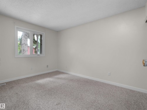 Carpeted flooring with white baseboards, light-toned wall paint, and a window with white trim - #47 1904 48 St Nw, Edmonton, AB - Indoor Photo Showing Other Room