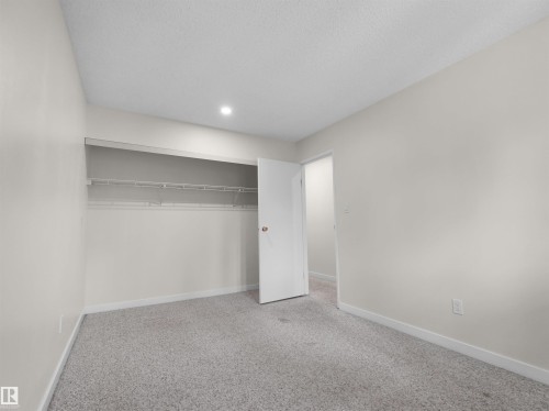 Recessed ceiling light, wall-to-wall carpeting, and a built-in closet with shelving and hanging rod - #47 1904 48 St Nw, Edmonton, AB - Indoor Photo Showing Other Room