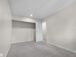 Recessed ceiling light, wall-to-wall carpeting, and a built-in closet with shelving and hanging rod - 