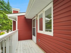 Outdoor balcony with white railing, red horizontal siding, and white window trim - 