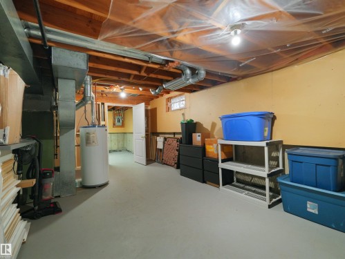 Unfinished basement with exposed wood joists, painted concrete flooring, and visible ductwork - #47 1904 48 St Nw, Edmonton, AB - Indoor Photo Showing Basement