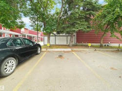 Paved parking area with marked spaces and surrounding mature trees - 