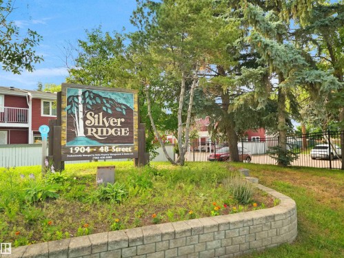 Community entrance sign with stone retaining wall, mature trees, and landscaping - #47 1904 48 St Nw, Edmonton, AB - Outdoor