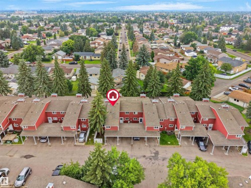 Townhouse community with red-sided units, individual carport parking, and mature evergreen trees - #47 1904 48 St Nw, Edmonton, AB - Outdoor With View