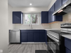 Kitchen featuring navy cabinetry, white countertops, stainless steel appliances, a white subway tile backsplash, and wood-finish flooring - 
