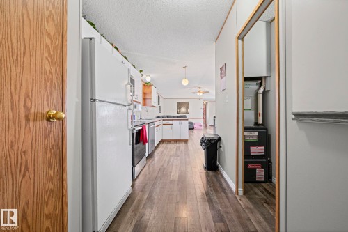 Wood-finish flooring throughout, white kitchen cabinetry, and stainless-steel appliances - 89 Springfield Crescent, Spruce Grove, AB 
