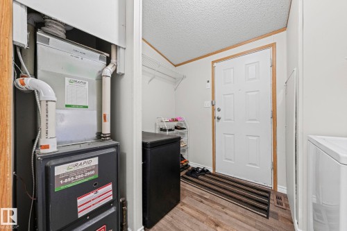 Wood-finish flooring with a white paneled door and light-toned walls - 89 Springfield Crescent, Spruce Grove, AB 
