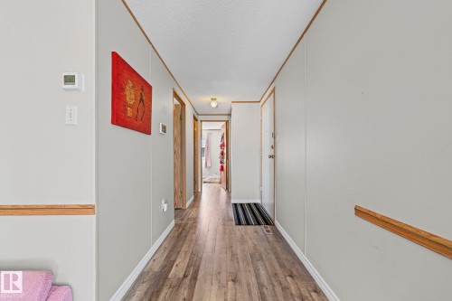 Hallway featuring wood-finish flooring, light grey walls, and wood trim accents - 89 Springfield Crescent, Spruce Grove, AB 