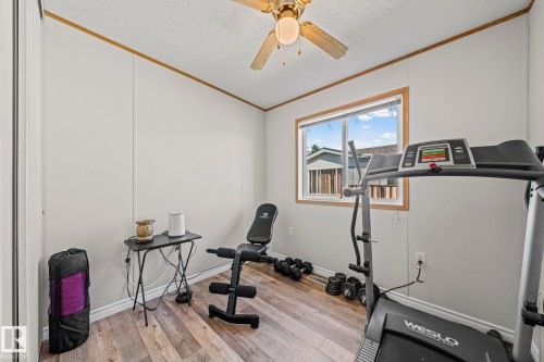 Wood-finish flooring, light-toned wall paneling, window with wood-trim, and a ceiling fan with integrated lighting - 89 Springfield Crescent, Spruce Grove, AB 