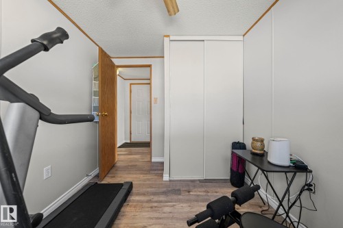 Versatile bedroom or home office space featuring hardwood flooring, white panel closet doors, and white painted walls - 89 Springfield Crescent, Spruce Grove, AB 