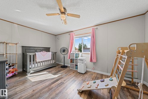 Wood-finish flooring, ceiling fan with light fixture, window with drapes, light gray wall panels, and white trim - 89 Springfield Crescent, Spruce Grove, AB 