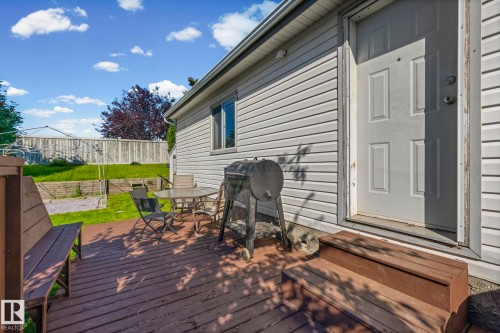 Rear exterior featuring wood-finish siding, a paneled door, a wooden deck, and a wooden bench - 89 Springfield Crescent, Spruce Grove, AB 