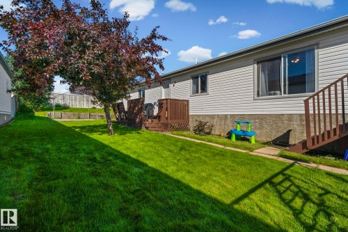 Expansive backyard with a manicured lawn, established landscaping, and a wooden deck - 89 Springfield Crescent, Spruce Grove, AB 