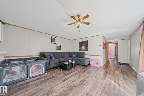Wood-finish flooring throughout, ceiling fan with light fixture, and light-toned wall panels with wood trim - 89 Springfield Crescent, Spruce Grove, AB 