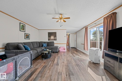 Spacious living area featuring wood-finish flooring, a ceiling fan, and sliding glass doors - 89 Springfield Crescent, Spruce Grove, AB 