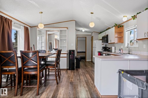 Open-concept living space with wood-finish flooring, white cabinetry, and recessed lighting - 89 Springfield Crescent, Spruce Grove, AB 