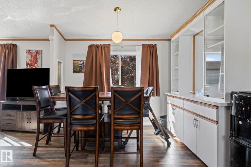 Wood-finish flooring, built-in white cabinetry, and a central pendant light fixture - 89 Springfield Crescent, Spruce Grove, AB 