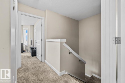 Carpeted hallway with painted walls and a staircase featuring a white handrail - 11436 88 Street Nw, Edmonton, AB - Indoor Photo Showing Other Room