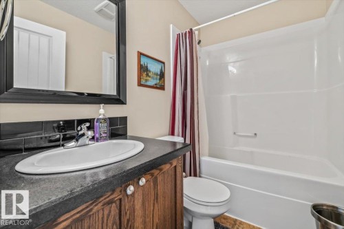 White oval basin with a chrome faucet, dark countertop, and wood-finish vanity cabinetry - 11436 88 Street Nw, Edmonton, AB - Indoor Photo Showing Bathroom