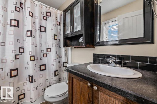 Wood-finish vanity with an integrated sink and chrome faucet - 11436 88 Street Nw, Edmonton, AB - Indoor Photo Showing Bathroom