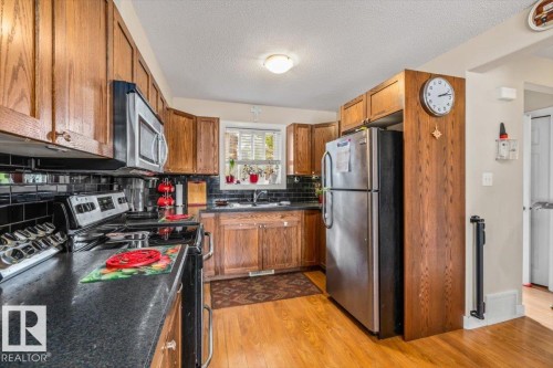 Wood-finish cabinetry paired with black subway tile backsplash - 11436 88 Street Nw, Edmonton, AB - Indoor Photo Showing Kitchen With Double Sink