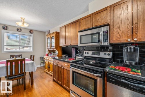 Wood-finish flooring with full-height cabinetry, stainless steel appliances, and a tiled backsplash - 11436 88 Street Nw, Edmonton, AB - Indoor Photo Showing Kitchen