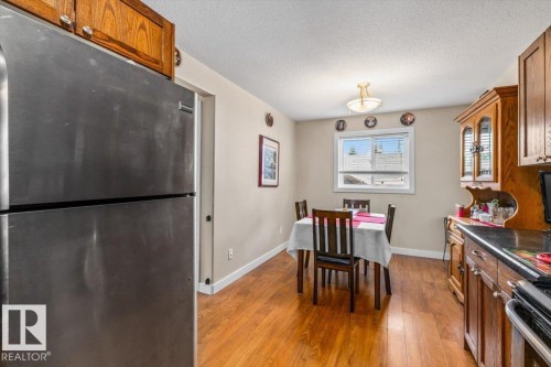Wood-finish flooring throughout, stainless steel refrigerator, wood cabinetry, built-in display hutch, and a window for natural light - 11436 88 Street Nw, Edmonton, AB - Indoor Photo Showing Other Room