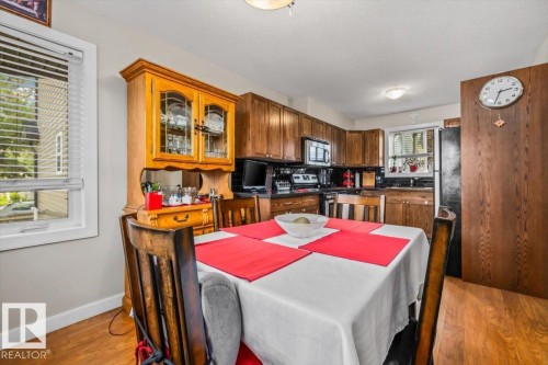 Kitchen featuring wood-finish flooring, dark wood-finish cabinetry, black countertops, and a full suite of appliances - 11436 88 Street Nw, Edmonton, AB - Indoor Photo Showing Dining Room