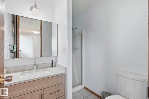 Vanity with light-toned cabinetry, an integrated sink, and a light-colored countertop - 10007 168 Avenue Nw, Edmonton, AB - Indoor Photo Showing Bathroom